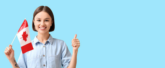 Wall Mural - Beautiful young woman with Canadian flag showing thumb-up on light blue background with space for text