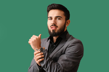 Wall Mural - Young bearded man wearing stylish wristwatch on green background