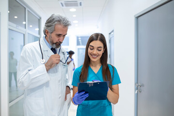 Wall Mural - Group of medics with clipboard discussing along hospital corridor. Doctor and nurse briefing medical report