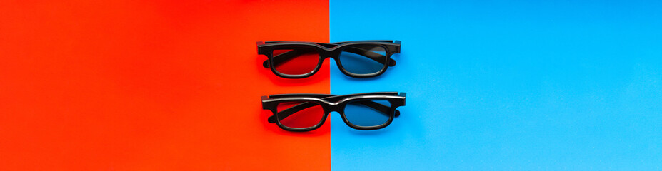 3D glasses for watching movies in the cinema and at home on a red-blue background close-up, two pairs of black 3D glasses banner. Cinema banner with place for text