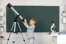 Cute Little Child With Telescope In Classroom At Elementary School.