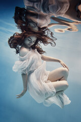 Wall Mural - A girl in a dress with lace swims underwater as if in zero gravity