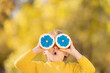 Surprised child holding slices of orange fruit like sunglasses