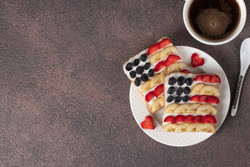 American flag sandwiches with fruit and cream cheese on rye bread and cup of coffee on brown background. Independence Day breakfast idea