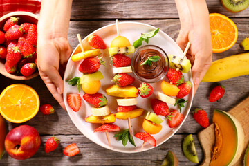 Wall Mural - hand holding platter with fruit skewer and chocolate