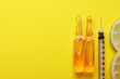 Pharmaceutical ampoules with medication, syringe and citrus slices on yellow background, flat lay. Space for text