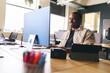 © Southworks - Young creative black man working on computer in modern office at desk smiling
