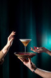Cocktail in a tall glass for vermouth on a velvety dark green background. Concept of mixology and bartending. Hands reaching for a cocktail