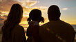 © Jade M/peopleimages.com - Silhouette closeup of happy family with one child on the beach looking at view at sunset. Two parents and daughter admiring golden sky and calm sea while enjoying their vacation and spending time