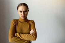 Studio Portrait Of Frowning Annoyed Angry And Offended Woman With Arms Crossed Looking At Camera Isolated On White Background With Copy Space For Your Content. Body Language. People And Emotions