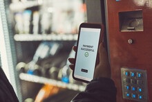 Consumer Paying For Product At Vending Machine Using Contactless Method Of Payment With Mobile Phone. Woman Using Payment App On Smartphone To Buy Product