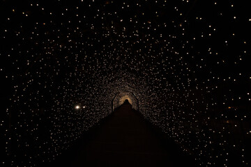Wall Mural - light tunnel (arch shape) with a fully black background reminder of halloween, a passage to hell, or