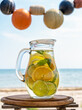 © TATIANA Z - Detox infused water with lime, oranges, mint on the beach with sea coast view
