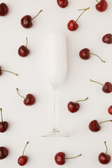 Wall Mural - Creative party composition with a glass of champagne and lots of fresh cherries on a white background. Trendy summer background. Flat lay.