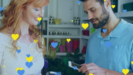 Poster - Animation of blue and yellow hearts over diverse people paying with smartphone