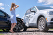 © bilanol - Sad young woman driver standing near her smashed car looking shocked on crashed vehicles in road accident