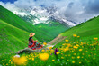 © tawatchai1990 - Tourist sitting on the rock at green pasture against highest georgian mountain Shkhara near Ushguli in Georgia.