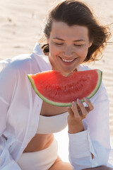 Wall Mural - portrait of cheerful young woman in white shirt holding tasty watermelon.