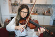 © Miljan Živković - One woman caucasian indoor in her house holding violin and learning to play front view waist up Study from home lifestyle concept
