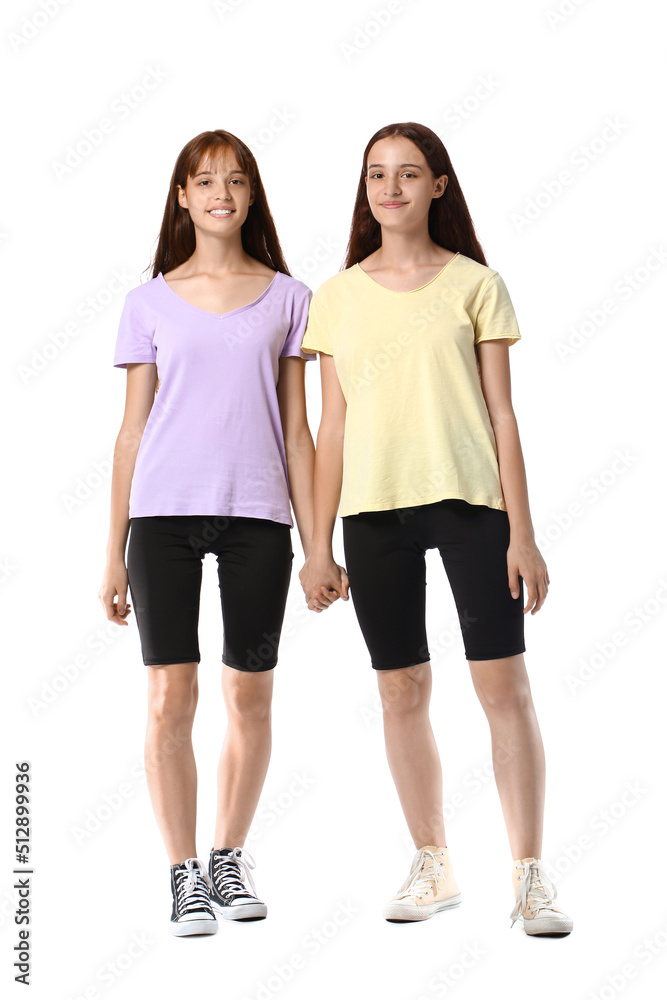 Teenage twin sisters holding hands on white background