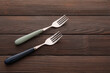 Stylish stainless steel forks on dark wooden background