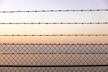 Barbed Wire Fence Over Sky And Sea At Sunset Warm Colors Background Full Frame