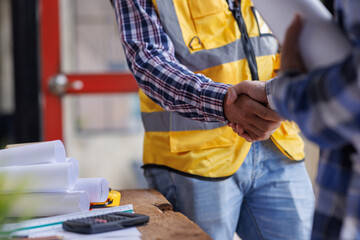 Architect contractor shaking hands with client after seal a deal to renovate building, engineer handshake partnership and contractor concept