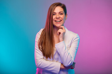 Smilng business woman touching her chin, face, isolated portrait with neon lights colors effect. Female model on neon colored background wearing white suit.