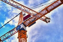Crossing Yellow Outriggers Of Construction Cranes Against Cloudy Blue Sky, Abstract