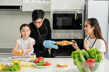 Overjoyed young family with little preschooler kids have fun cooking baking pastry at home together, happy smiling parents enjoy weekend cooking in kitchen