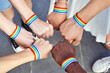 © JoseIMartin - Group of multiracial people putting hands together with LGBT rainbow flag wristbands. Diversity, pride, equality and unity concept.