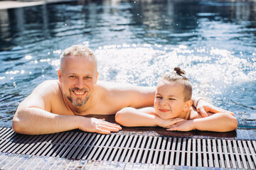 Wall Mural - A middle-aged dad and his little son have fun in the pool.