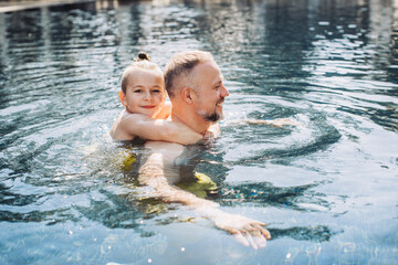 Wall Mural - Young dad teaching his little son to swim in swimming pool.