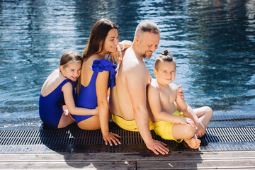 Wall Mural - Happy family with two kids having fun in the swimming pool. Summer vacation concept