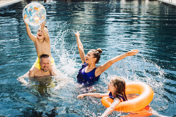 Wall Mural - Happy family with two kids having fun in the swimming pool. Summer vacation concept