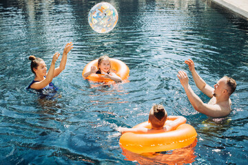 Wall Mural - Happy family with two kids having fun in the swimming pool. Summer vacation concept