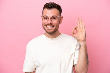 Wall Mural - Young brazilian man isolated on pink background With glasses and doing OK sign