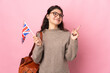Young Russian woman holding an United Kingdom flag isolated on pink background pointing up a great idea