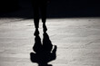 Silhouette of girl walking down the street, black shadow on pavement. Concept of loneliness, city life