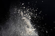 © TSViPhoto - Flying white flour, powder on a black background. Spray of particles, lumps, pieces of white matter.Sweeping dry dust, paint, farina