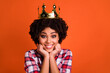 Photo of cheerful adorable girl hands touch cheeks toothy smile wear crown isolated on orange color background