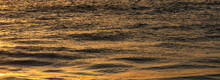 Calm Ocean Surface Reflecting Golden Light At Sunrise