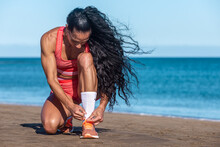 Latin Athlete Tying Shoelace Before Exercise On Beach