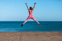 Sporty Woman Jumping And Enjoying Freedom At The Beach