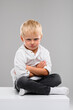 © flywish - A small fair-haired boy in a shirt and pants sits on a white cube. Portrait. Spectrum of emotions
