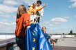 young woman holding eu flag near blurred multicultural friends outdoors.