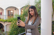 © Hugo - Serious business girl making a video call with her smart phone on a hotel balcony.