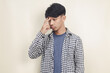Close-up portrait of young Asian male model wearing plaid shirt in doubt on isolated background