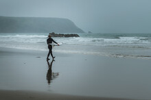 Male Surfer Heading Towards The Sea In Pembrokeshire, Wales