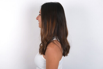 Profile portrait of nice young beautiful caucasian woman wearing white Top over white background, look empty space toothy smile